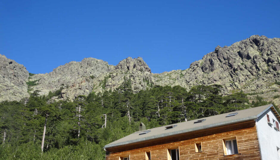 Klettern auf Korsika 6 a building with trees and mountains in the background